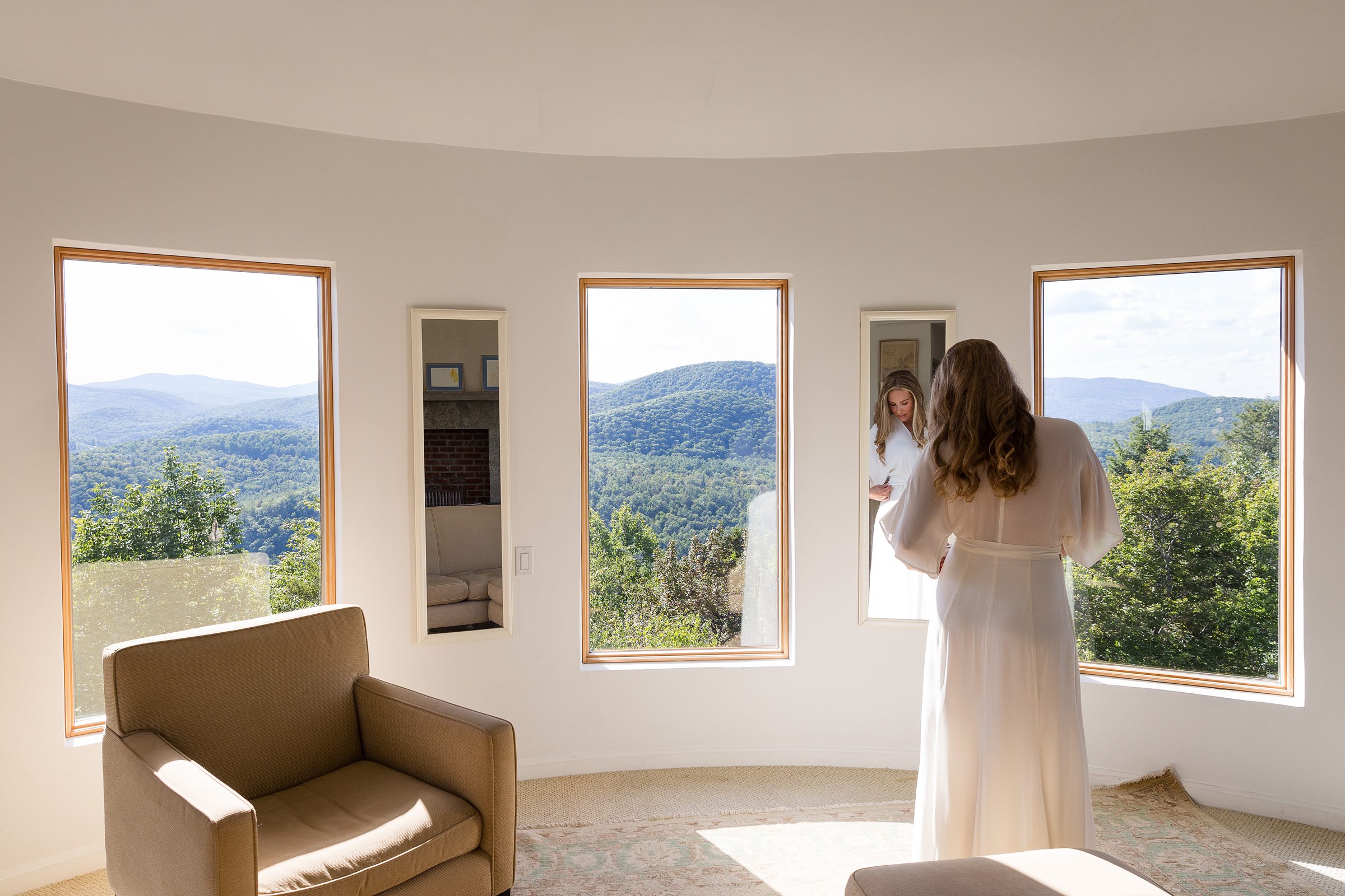 bride getting ready for elopement wedding looking out the window with mountain views 