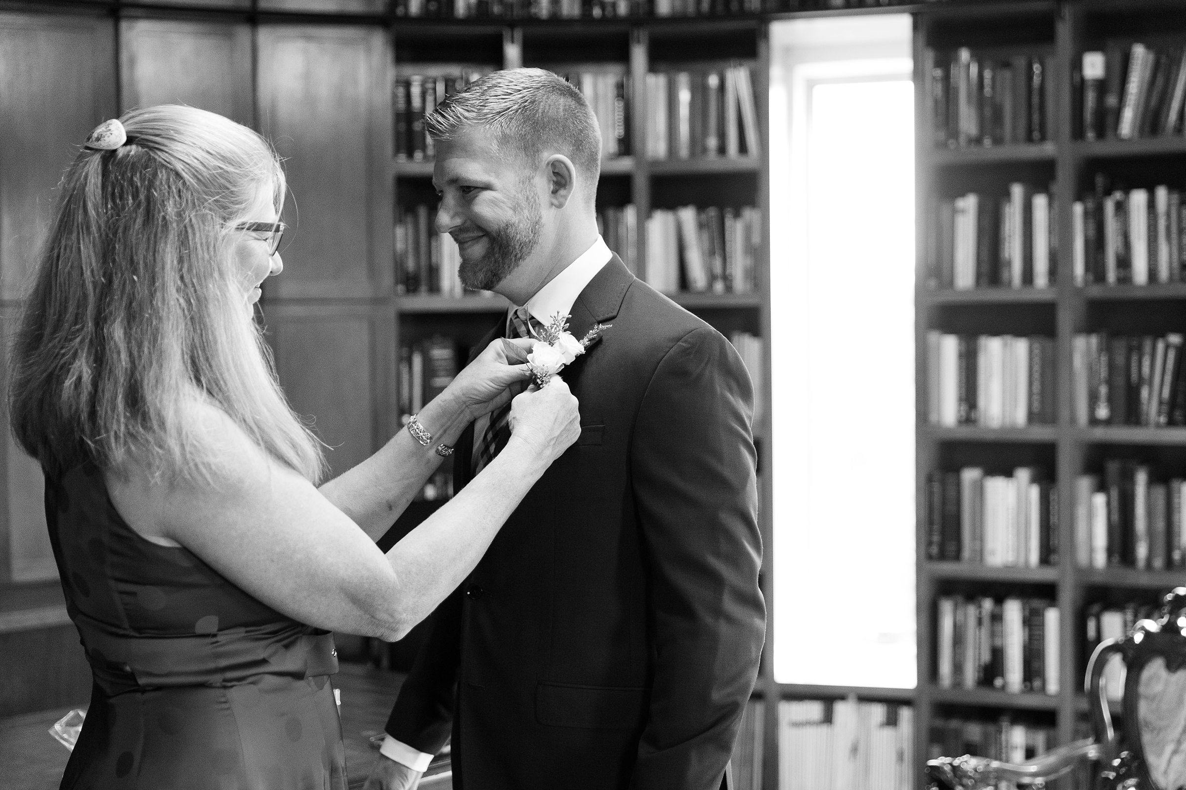 groom's mom putting on his boutonniere 