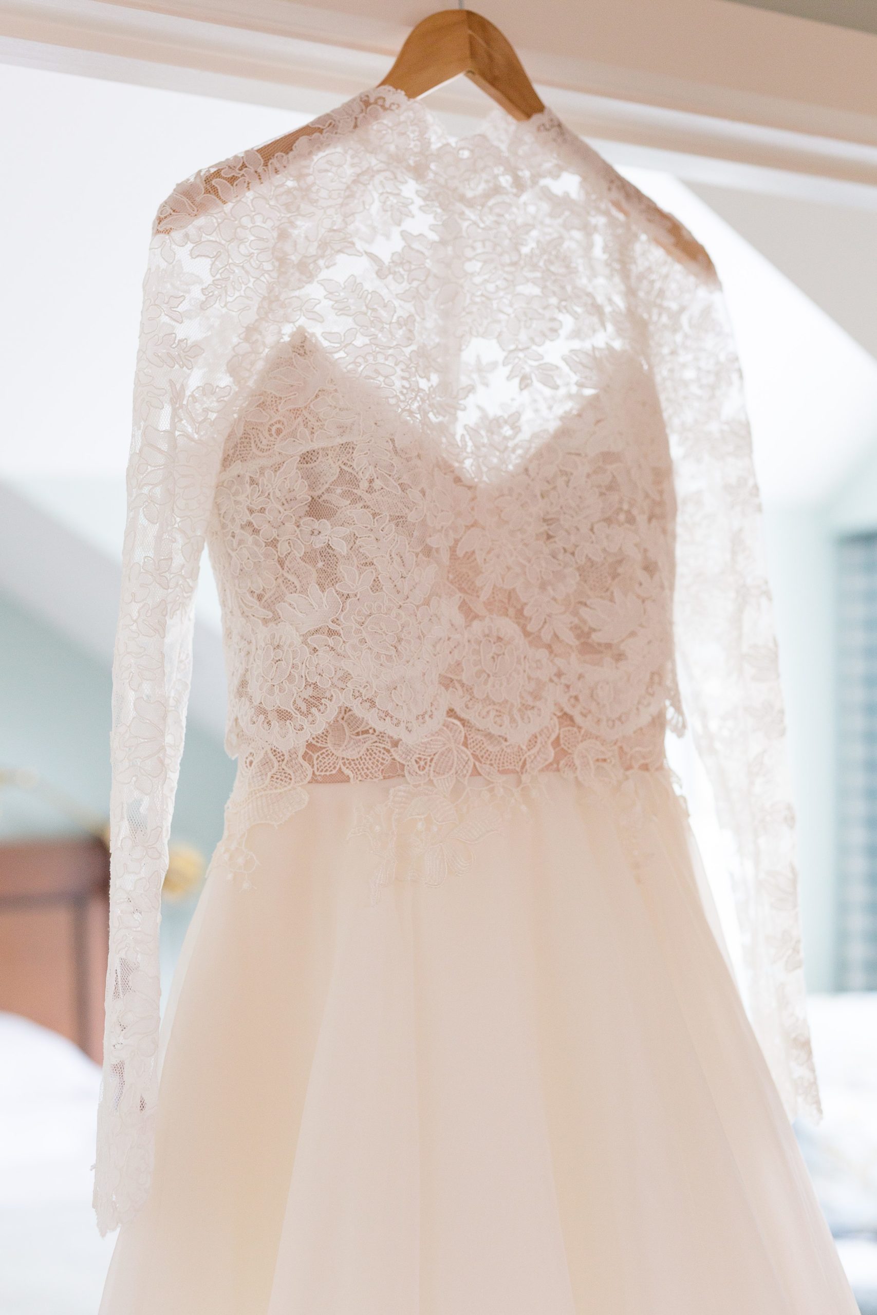 Long sleeve lace winter wedding dress hanging in the window