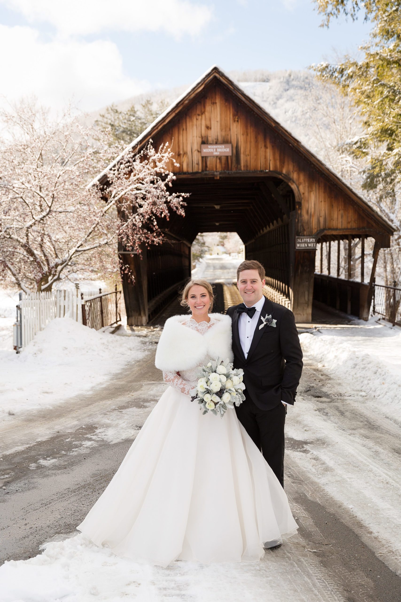 Bride and groom standing in front of wooden bridge for winter wedding at the Woodstock Inn