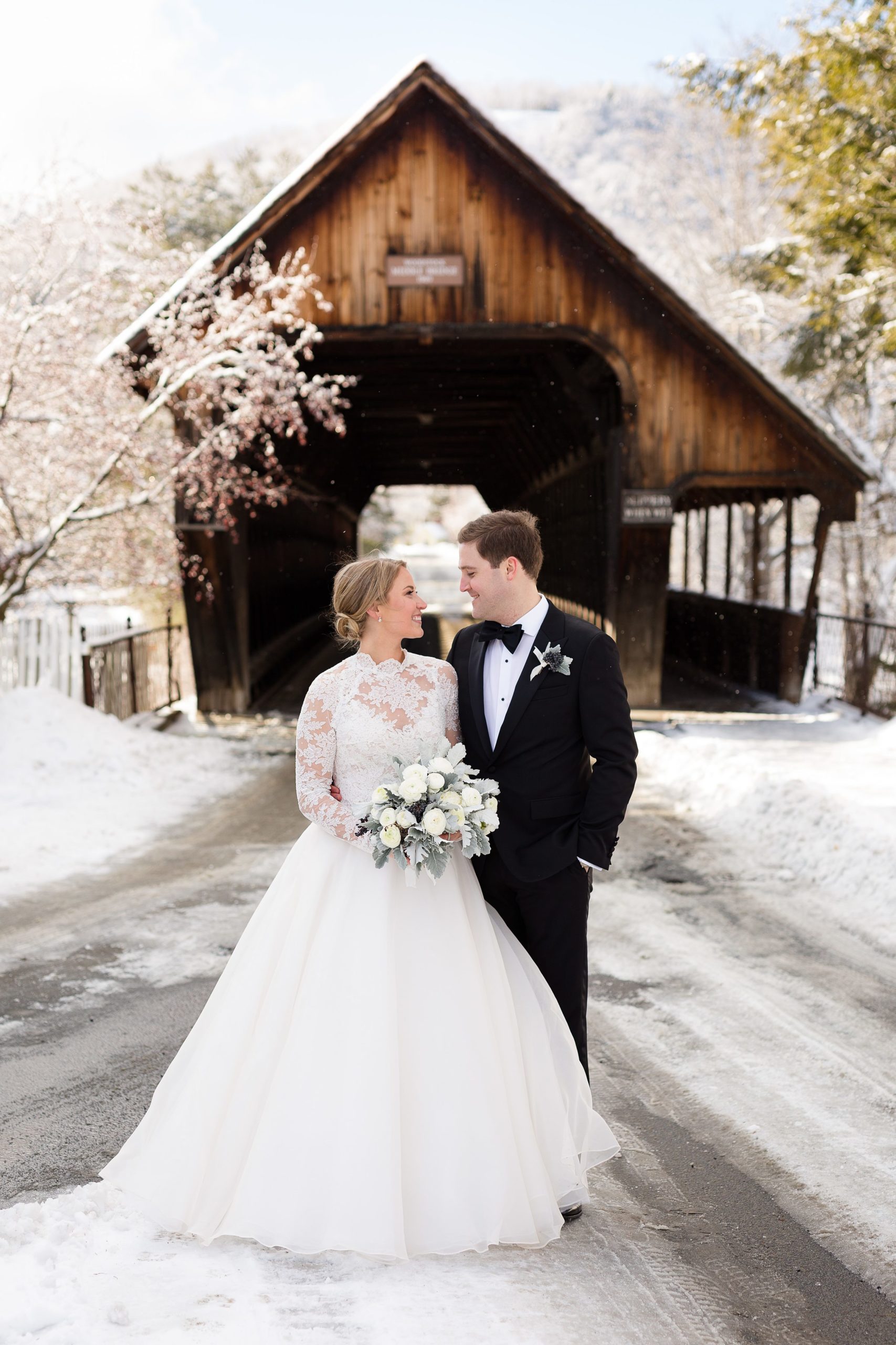 Bride and groom standing in front of wooden bridge at winter wedding