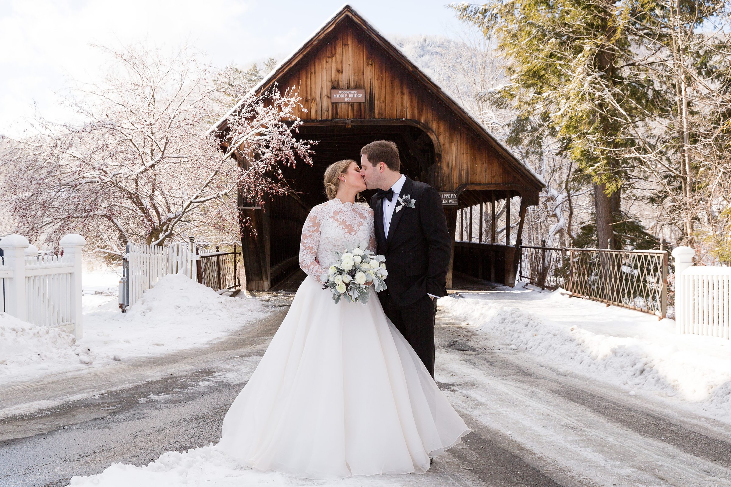 Bride and groom standing in front of wooden bridge for winter wedding
