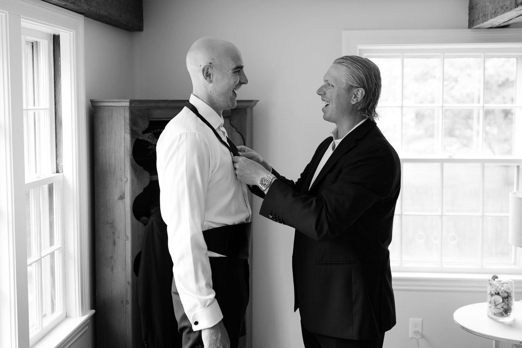 groomsman helping tie the groom's bowtie