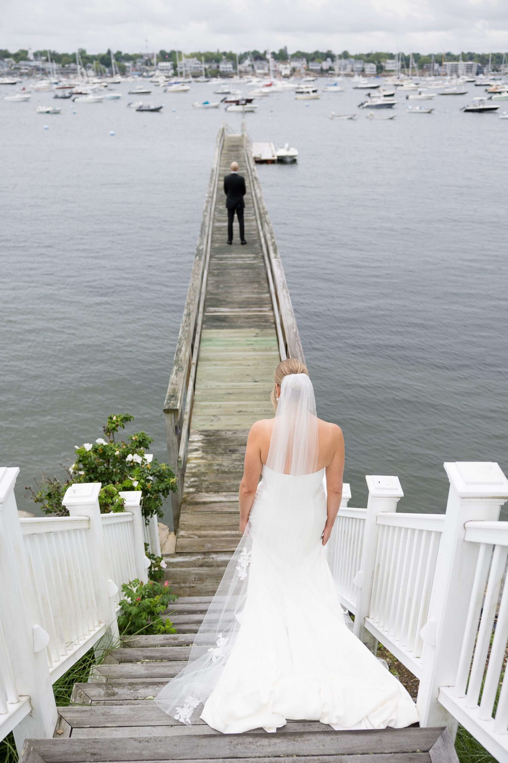 bride walking up behind the groom on a pier before the first look