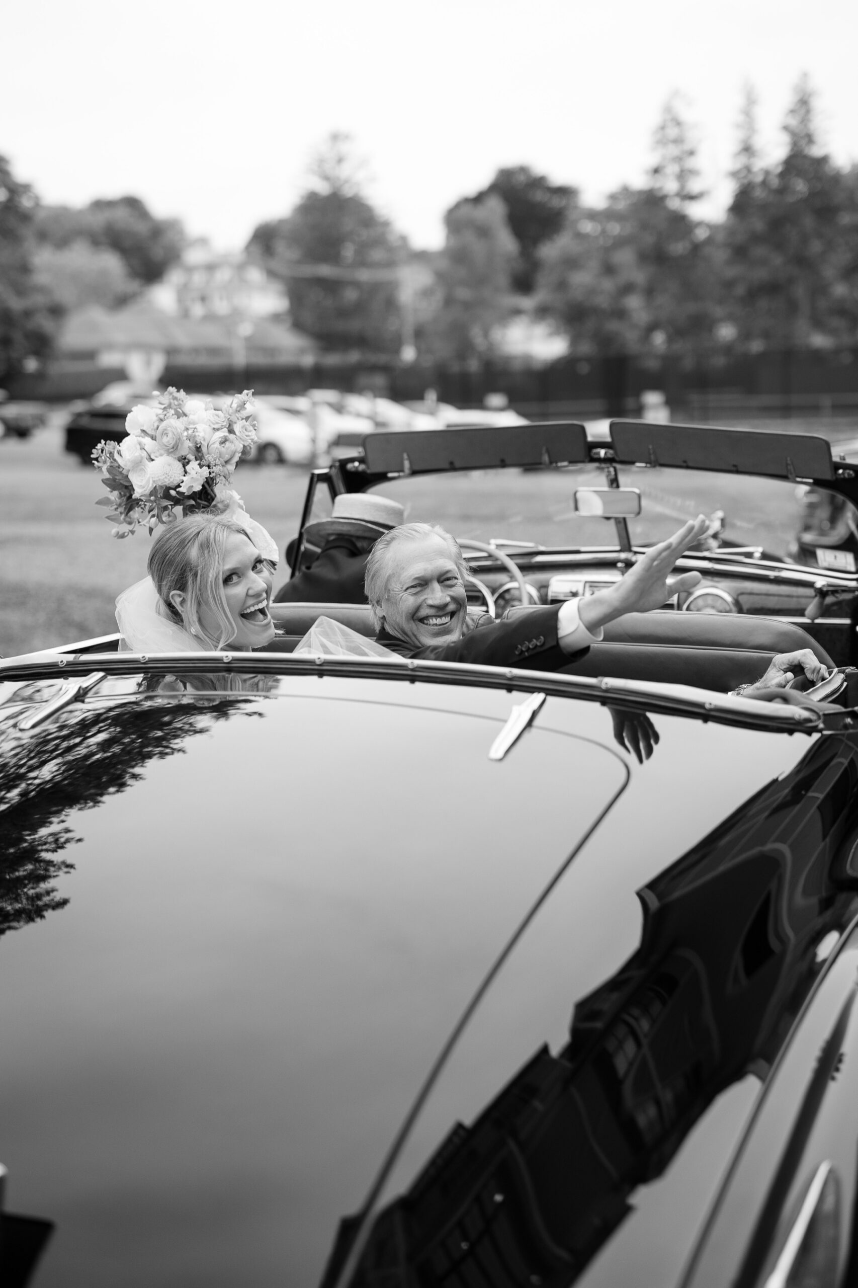 bride and her father waving from the back of the vintage car