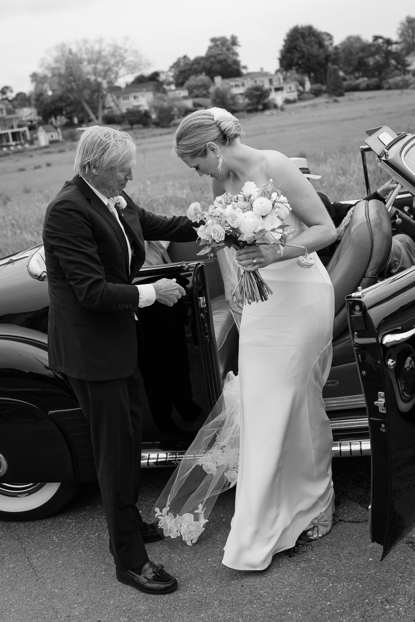 bride stepping out of vintage car with her dad