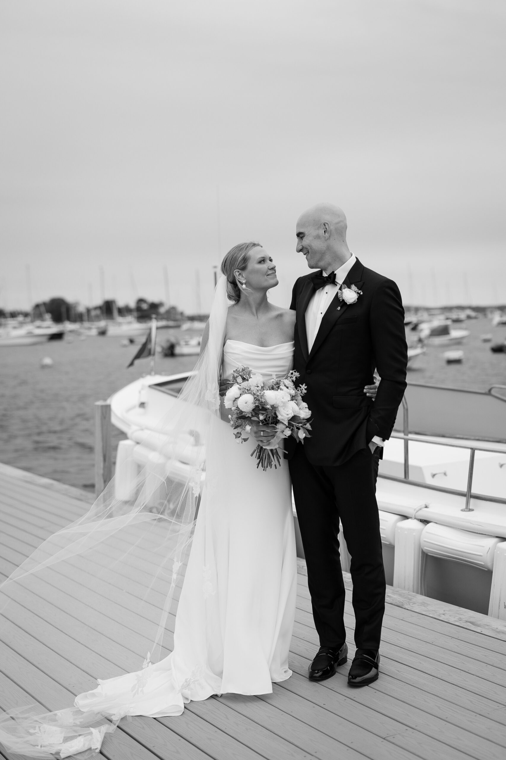 bride and groom smiling at each other standing on the dock