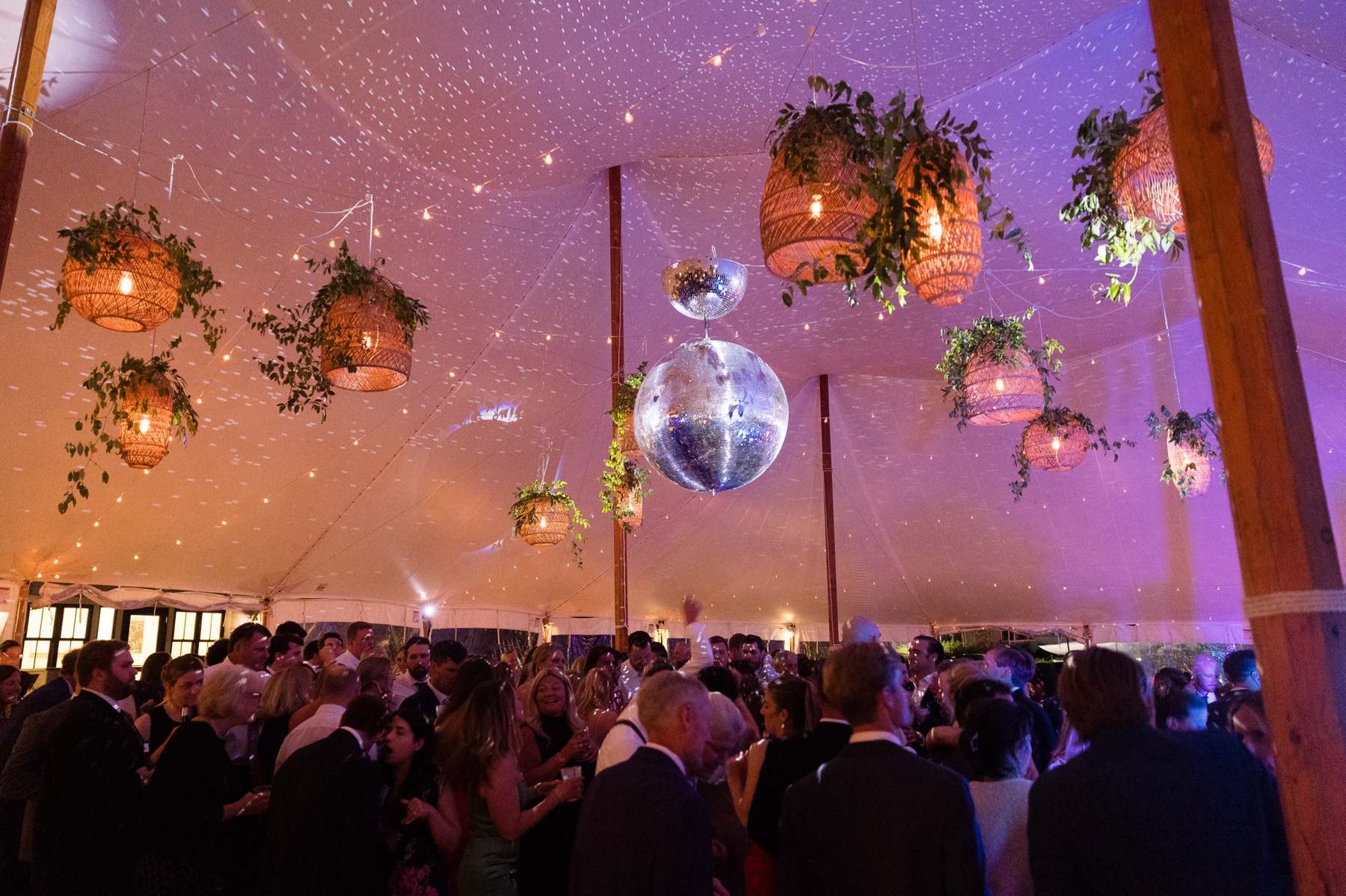 wide shot of the crowd dancing in the tent with disco balls and sparkling lights