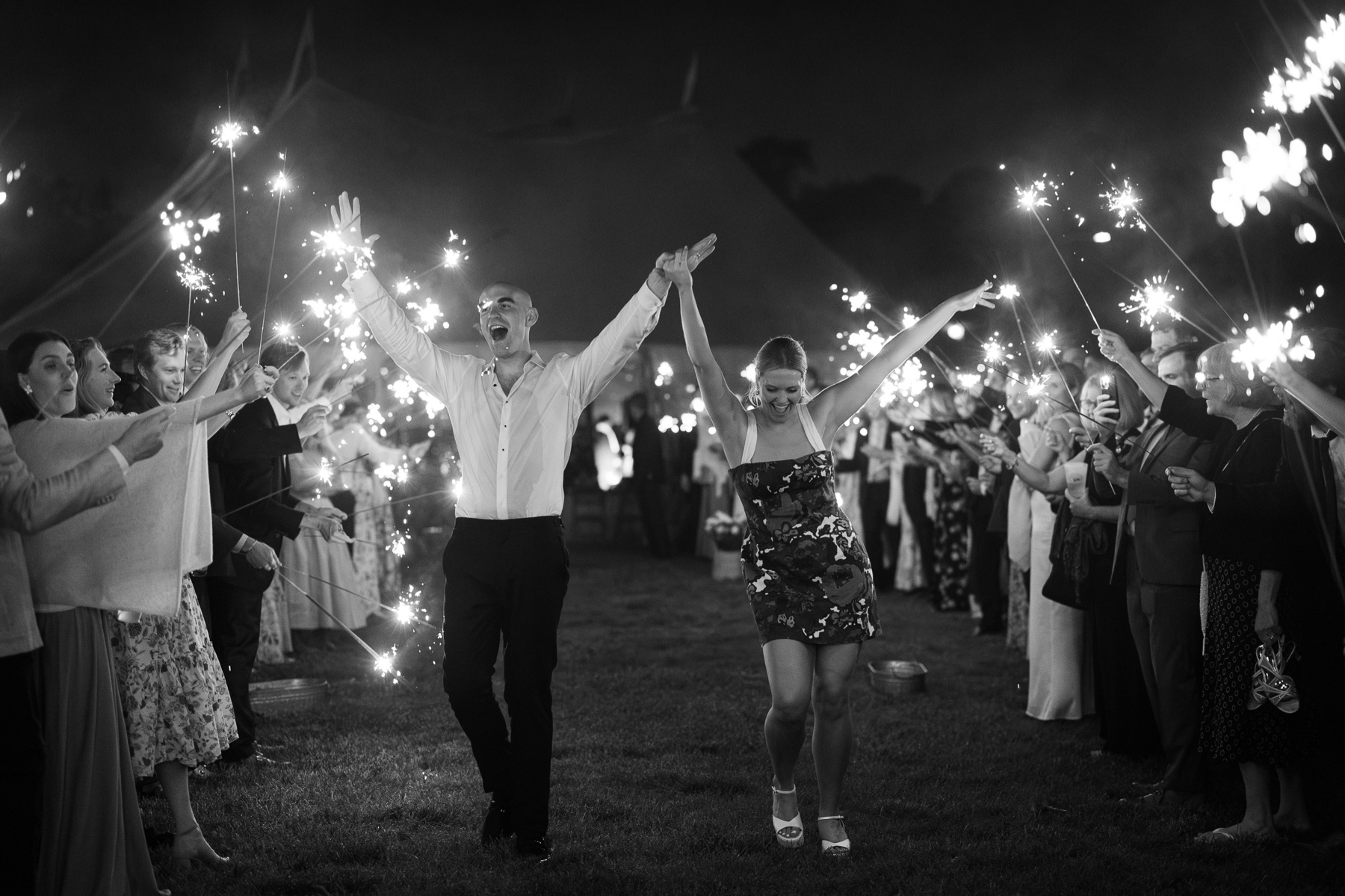 bride and groom walking through sparkler lane with guests